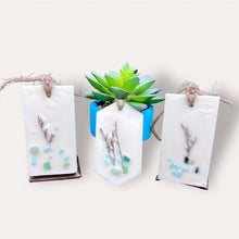 Load image into Gallery viewer, Calming Creek Sachets by Pure Essence Scent-white scented wax decorated with dried botanicals and pebbles for decoration, and twine loop for hanging.