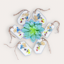 Load image into Gallery viewer, Mango Ciruela Sachets by Pure Essence Scent-white scented wax decorated with dried botanicals and pebbles for decoration, and twine loop for hanging.