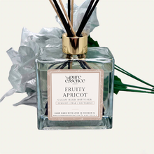 Load image into Gallery viewer, Fruity Apricot Reed Diffuser by Pure Essence Scent-A glass reed diffuser filled with scented liquid. There’s a gold cap and black/natural reeds, some featuring decorative flowers.