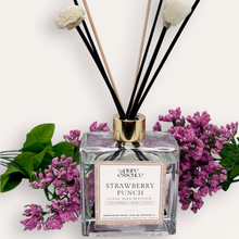 Load image into Gallery viewer, Strawberry Punch Reed Diffuser by Pure Essence Scent-A glass reed diffuser filled with scented liquid. There’s a gold cap and black/natural reeds, some featuring decorative flowers.